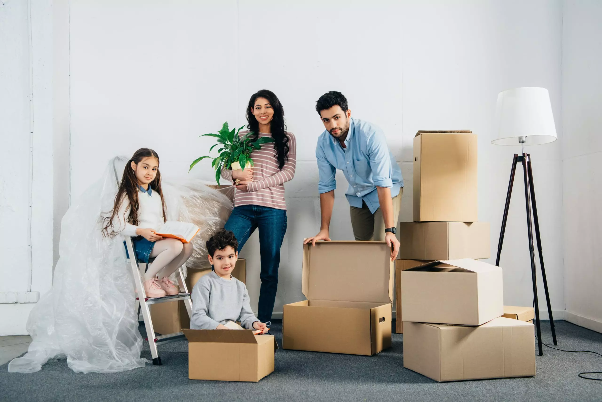 Cheerful latin family standing near boxes while moving into new home